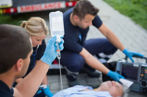 Ambulancier tenant goutte à goutte tout en aidant l'homme — Photo