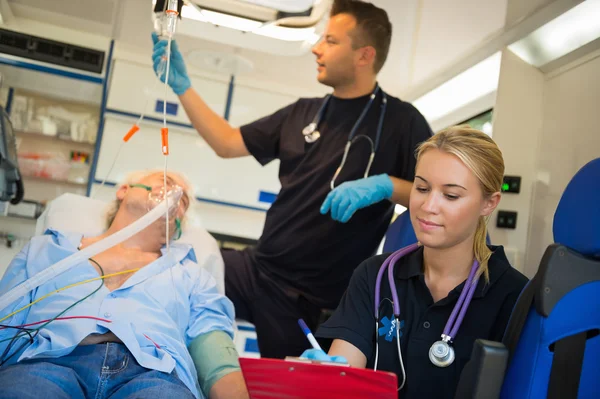 Equipe paramédica tratando o homem em ambulância — Fotografia de Stock