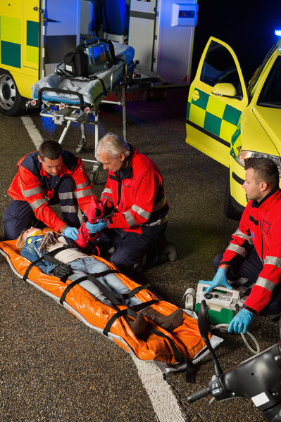 Парамедики помогают водителю мотоцикла на носилках
