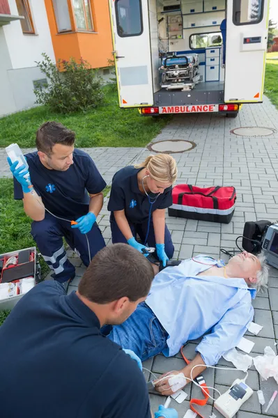 Paramedici che curano l'uomo ferito Immagine Stock