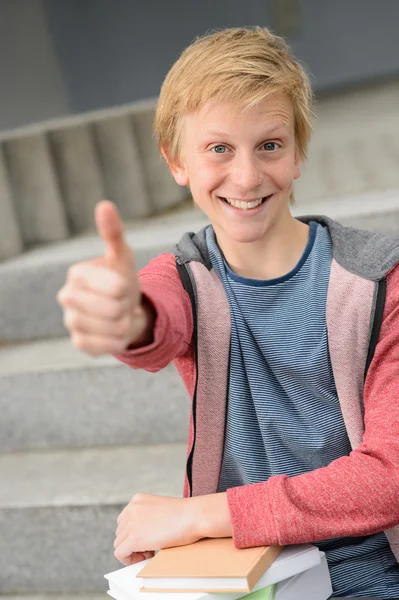 Студент с книгами показывает большой палец вверх — стоковое фото