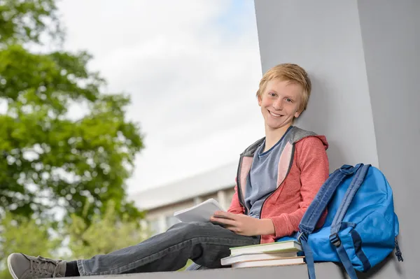 Menino estudando sentado na parede campus — Fotografia de Stock