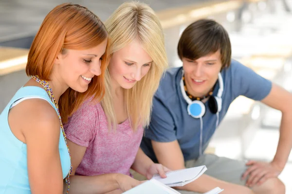 College vänner tittar in i bok — Stockfoto