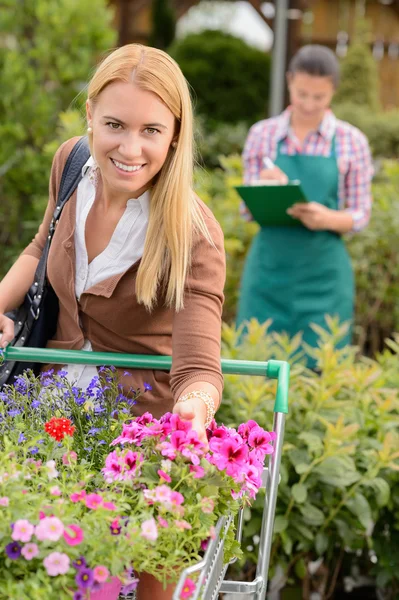 Oman lägga blommor i kundvagn — Stockfoto