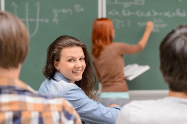 Matematik sınıfta otururken gülümseyen öğrenci kız