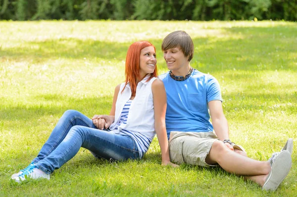 Adolescente casal sentado grama olhando uns aos outros — Fotografia de Stock