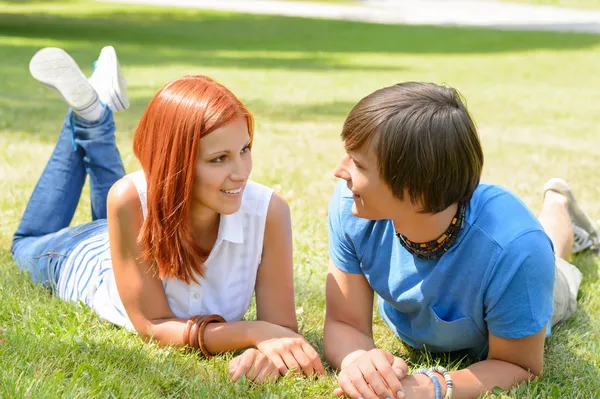 Paar liegt im Gras und schaut sich an — Stockfoto