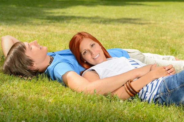 Couple d'adolescents profitant du soleil couché sur l'herbe — Photo