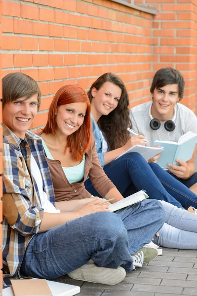 Estudiantes universitarios sentados afuera por la pared de ladrillo — Foto de Stock