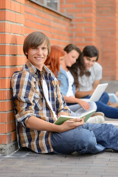 Çocuğu yere kampüs dışında oturan arkadaşlar okuyan — Stok fotoğraf