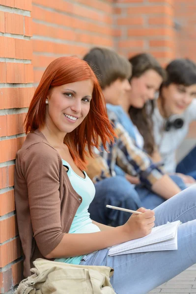 Étudiante assise à l'extérieur du campus avec des amis — Photo