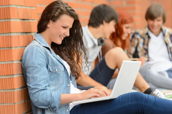 Student meisje met laptop en vrienden buiten — Stockfoto