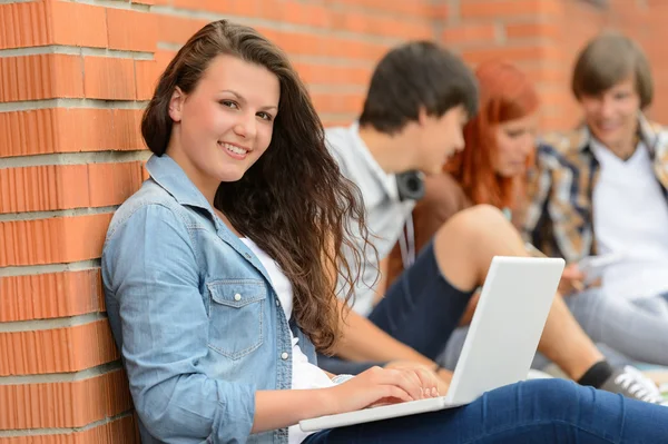 Студентка за пределами кампуса с друзьями по ноутбуку — стоковое фото