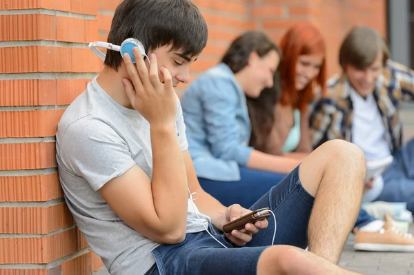 Student jongen met hoofdtelefoon vrienden buiten de campus — Stockfoto