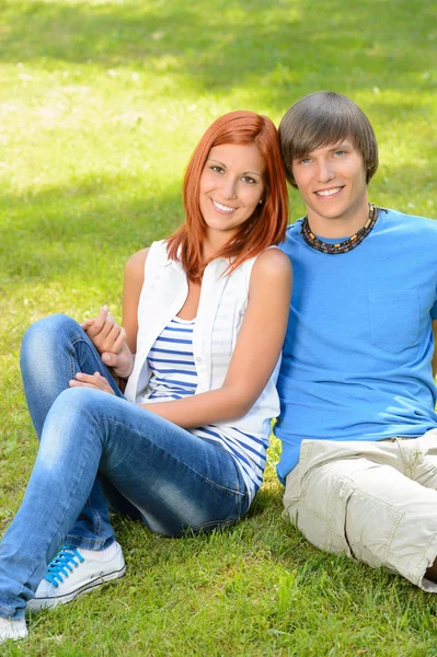 Adolescente casal sentado na grama abraçando verão Imagens De Bancos De Imagens
