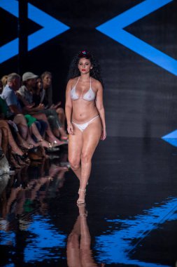 Miami Beach 'teki Faena Forum' da Sanat, Kalpler, Moda Yüzme Haftası 'nda Riskli Dukes Yüzme Moda Şovu için podyumda bir manken yürüyor.
