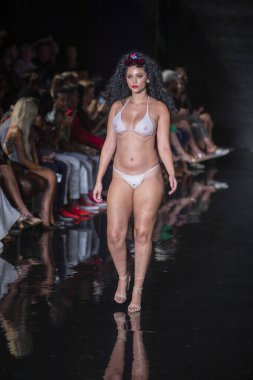 Miami Beach 'teki Faena Forum' da Sanat, Kalpler, Moda Yüzme Haftası 'nda Riskli Dukes Yüzme Moda Şovu için podyumda bir manken yürüyor.