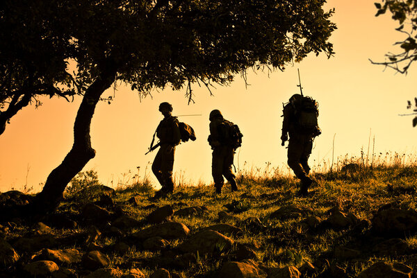 Three soldiers patrolling during sunset