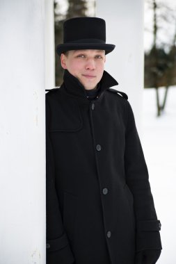 şapkalı adam beyaz sütun üzerinde dayanır.