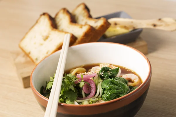 Bowl with brownish broth, shrimp and parsley — Stock Photo, Image