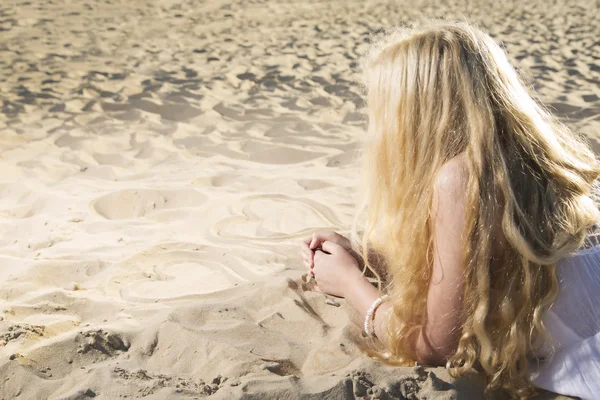 Vrouw in jurk tekenen harten op zand — Stockfoto