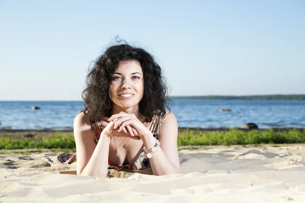 Mulher feliz com cabelos deitados na praia — Fotografia de Stock