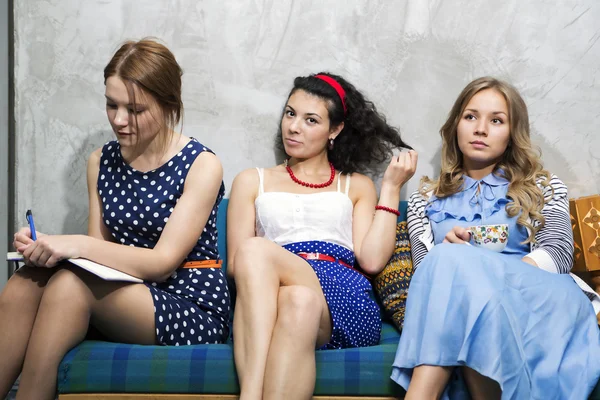 Womans in different dresses sit on sofa — Stock Photo, Image