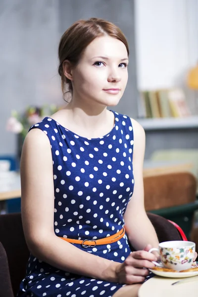 Vrouw in gevlekte jurk poseren in café — Stockfoto