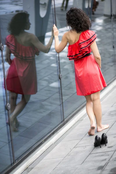 Frau in rotem Kleid läuft an Mauer entlang — Stockfoto