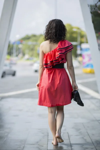 Femme en robe rouge marchant pieds nus — Photo