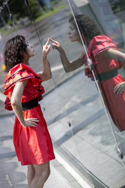 Woman in red dress scratching smooth glass — Stock Photo, Image