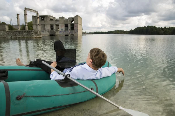 穿男人躺在湖上的船 — 图库照片