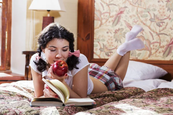 Woman in schoolgirl dress chews apple — Stock Photo, Image