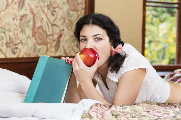 Pretty woman bite red apple at bed — Stock Photo, Image