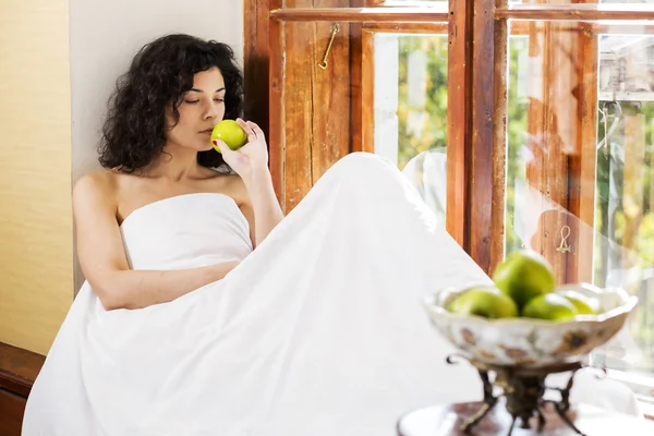 Woman smells green apple on wooden sill — Stock Photo, Image