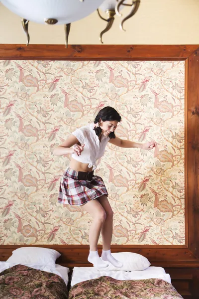 Woman in schoolgirl dress jump on bed