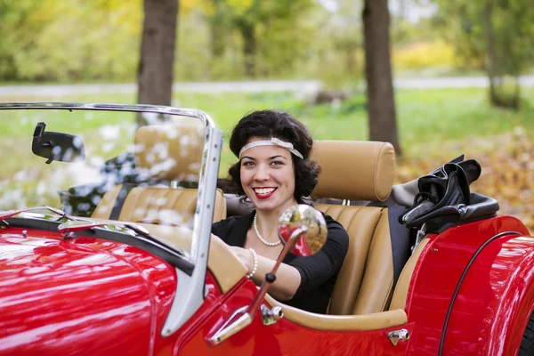 Sorrindo jovem mulher após roda de carro vermelho — Fotografia de Stock