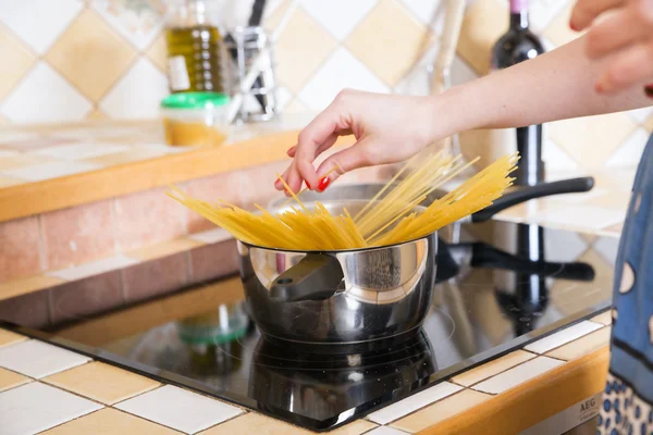 Woman put noodles at pot with water — Stock Photo, Image