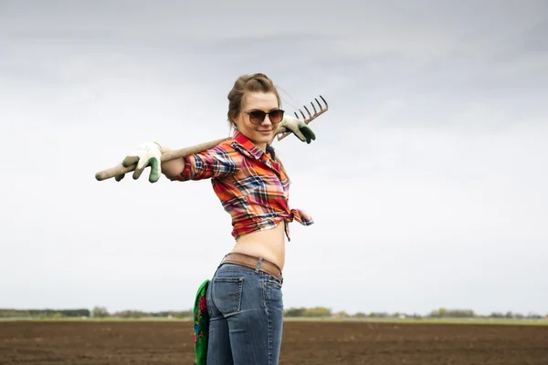 Woman holding worn rake and comfortable pose — Stock Photo, Image