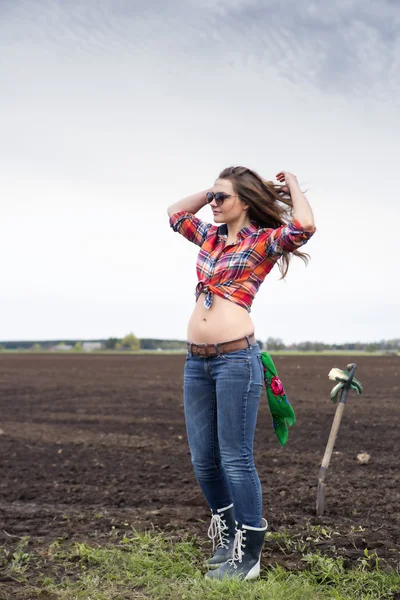 Woman adjusts long hair on cultivated field — Stock Photo, Image