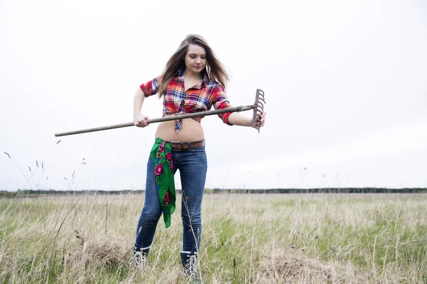 Woman cleans rake from stuck dry dirt — Stock Photo, Image