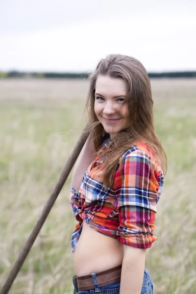 Woman and rake handle smile at camera — Stock Photo, Image