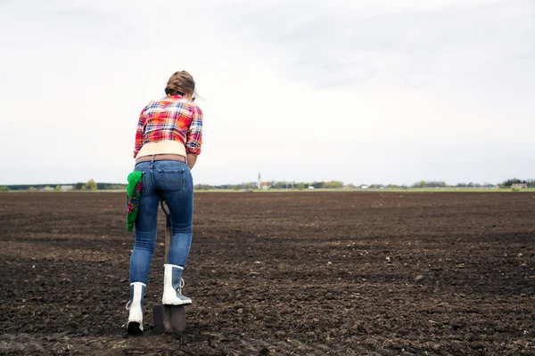 Женщина, стоящая на силовой лопате на землю — стоковое фото