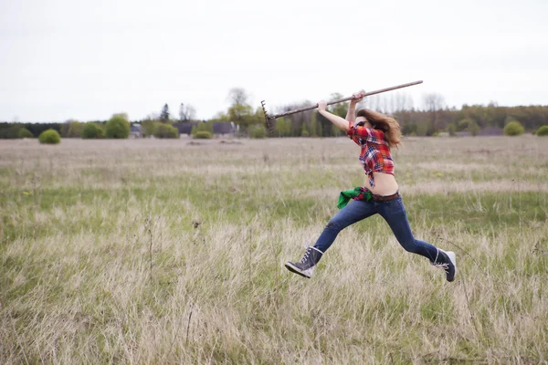 Kvinna med rake springa runt gård fältet — Stockfoto