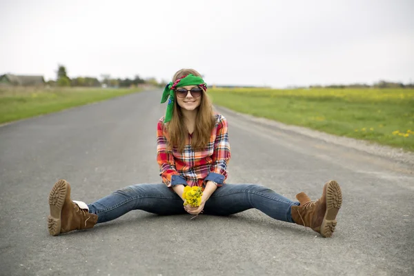 Mulher na estrada com flores amarelas pacote — Fotografia de Stock