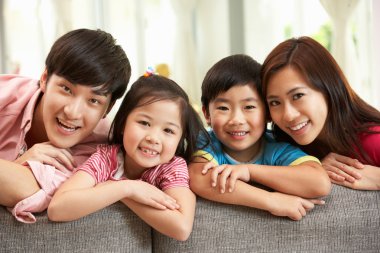 Chinese Family Sitting And Relaxing On Sofa Together At Home clipart