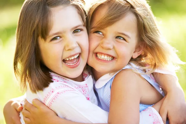 Two Young Girls Giving One Another Hug In Summer Field — Stock Photo, Image