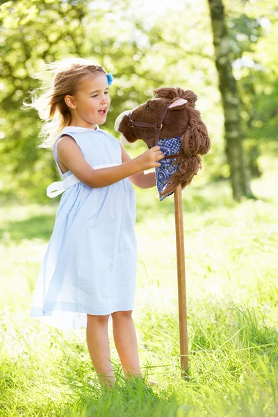 Jovem brincando com cavalo de passatempo no campo de verão — Fotografia de Stock