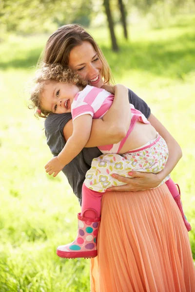 Mutter trägt kleine Tochter durch Sommerfeld — Stockfoto