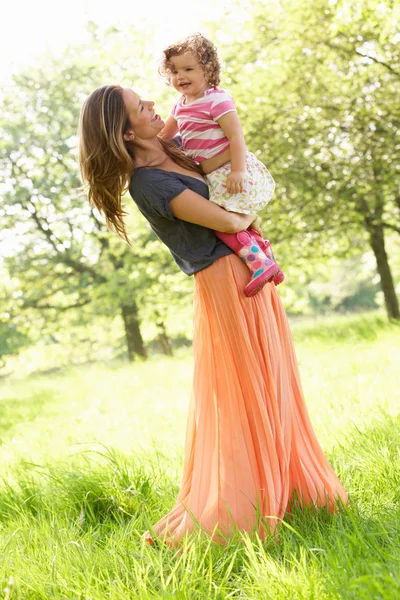 Madre llevando a su hija joven a través del campo de verano — Foto de Stock